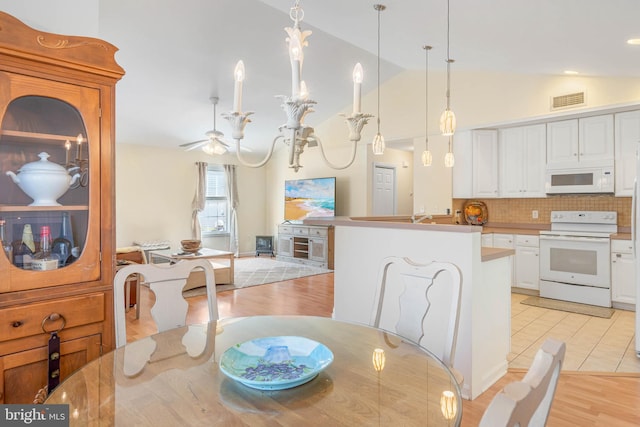 dining space with ceiling fan, lofted ceiling, and light hardwood / wood-style flooring