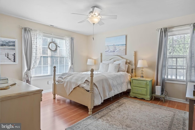 bedroom featuring ceiling fan, wood-type flooring, and multiple windows