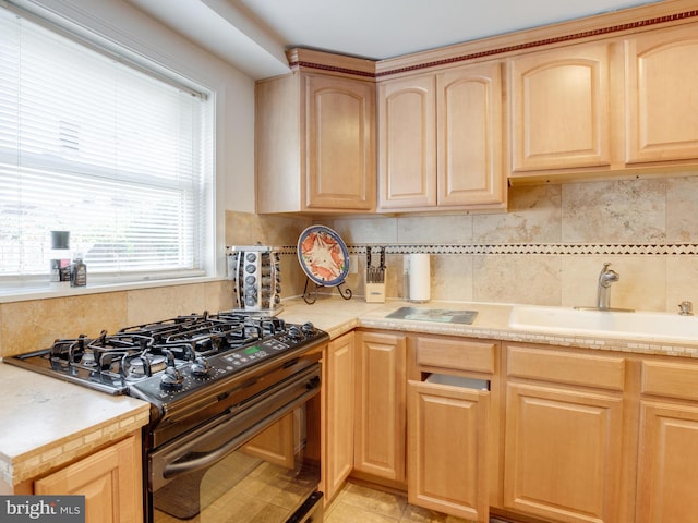 kitchen with black range with gas stovetop, sink, and light brown cabinetry