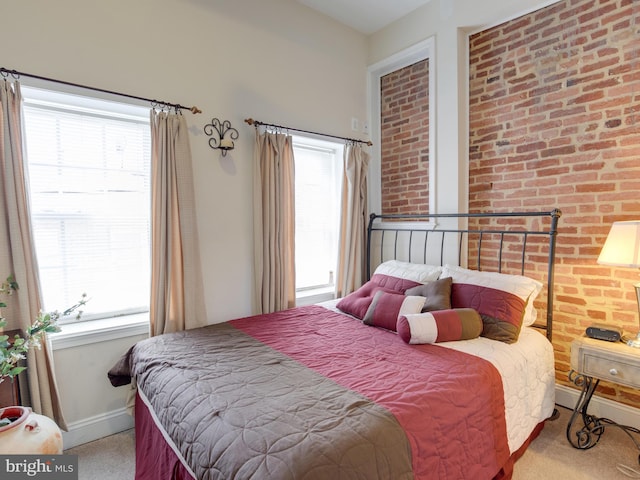 bedroom featuring light colored carpet, brick wall, and multiple windows