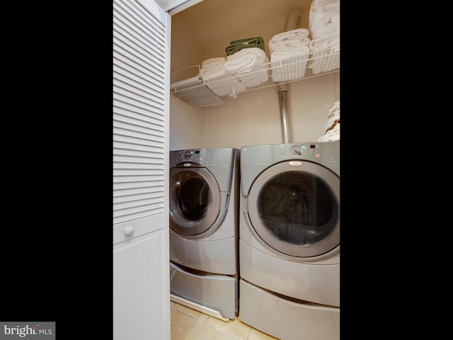 laundry area with washer and clothes dryer and light tile patterned floors