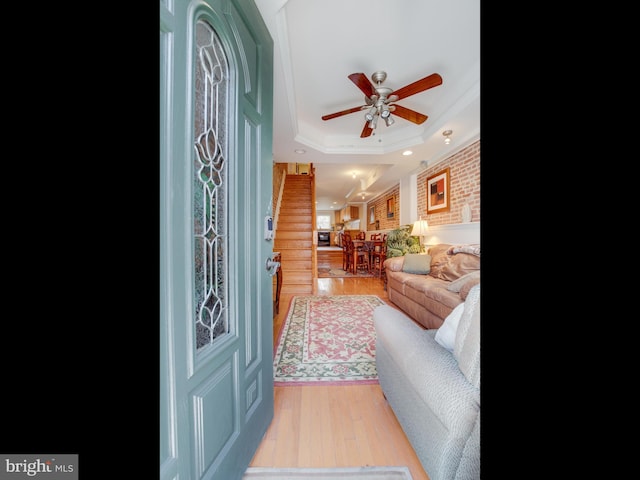 living room with a tray ceiling, ceiling fan, light hardwood / wood-style floors, and ornamental molding