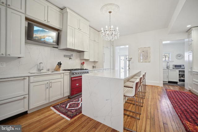 kitchen featuring sink, a center island, hardwood / wood-style floors, a kitchen bar, and stainless steel stove