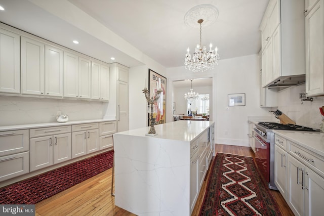 kitchen with a center island, high end stainless steel range oven, hanging light fixtures, light hardwood / wood-style flooring, and a chandelier