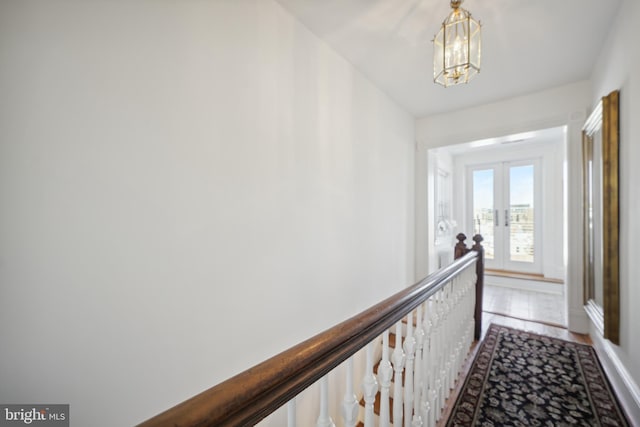 hall featuring hardwood / wood-style flooring, french doors, and an inviting chandelier