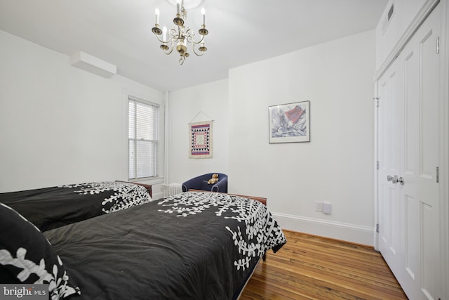 bedroom featuring hardwood / wood-style flooring, a chandelier, and a closet