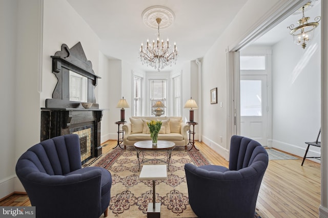 living area with a fireplace, hardwood / wood-style floors, and a notable chandelier