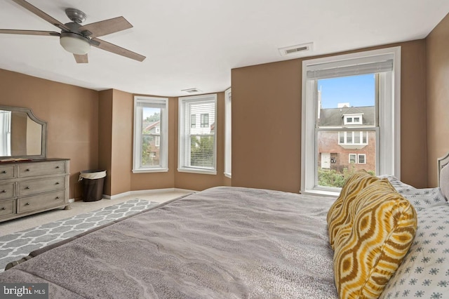 bedroom with ceiling fan, light colored carpet, and multiple windows