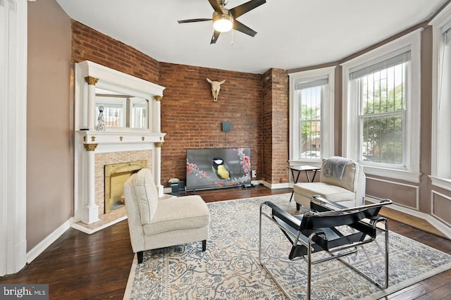 living room featuring ceiling fan, brick wall, and dark hardwood / wood-style floors