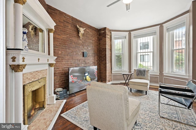 living room featuring hardwood / wood-style flooring, a wealth of natural light, ceiling fan, and brick wall