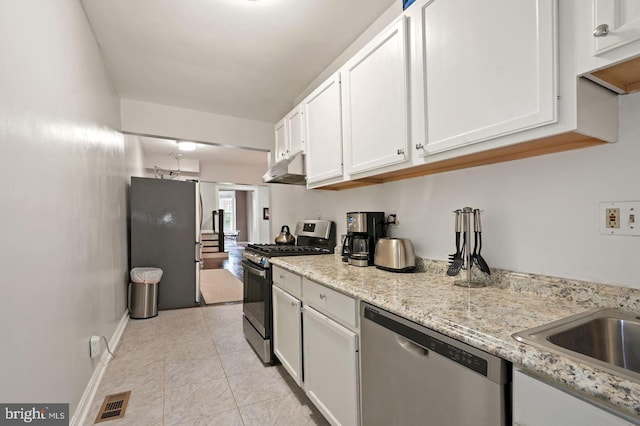 kitchen featuring white cabinets, light tile patterned flooring, light stone countertops, and appliances with stainless steel finishes