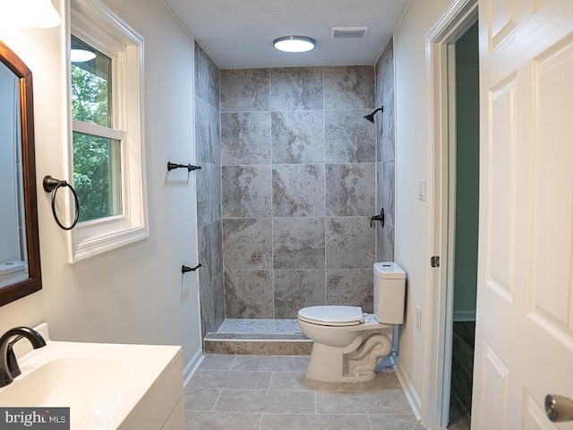 bathroom featuring tiled shower, tile patterned flooring, vanity, and toilet