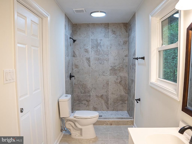 bathroom featuring a tile shower, toilet, plenty of natural light, and tile patterned floors