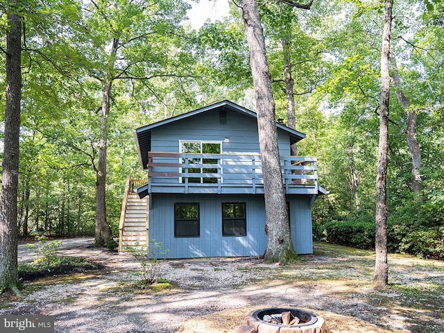 view of side of property featuring a wooden deck and a fire pit