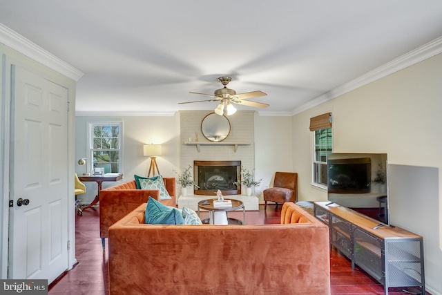 living room with ceiling fan, crown molding, dark wood-type flooring, and a brick fireplace