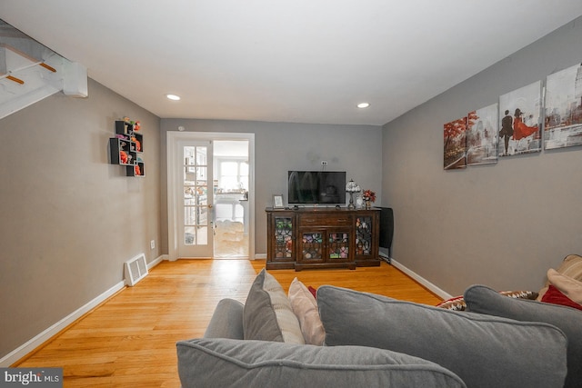 living room featuring beamed ceiling and light wood-type flooring