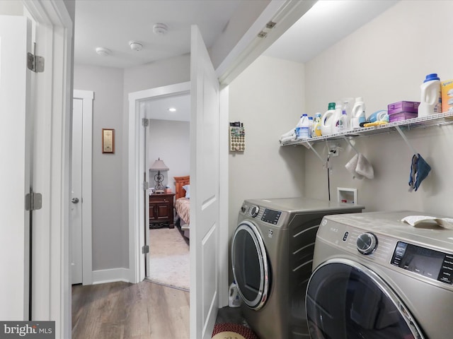 washroom with hardwood / wood-style flooring and washing machine and clothes dryer