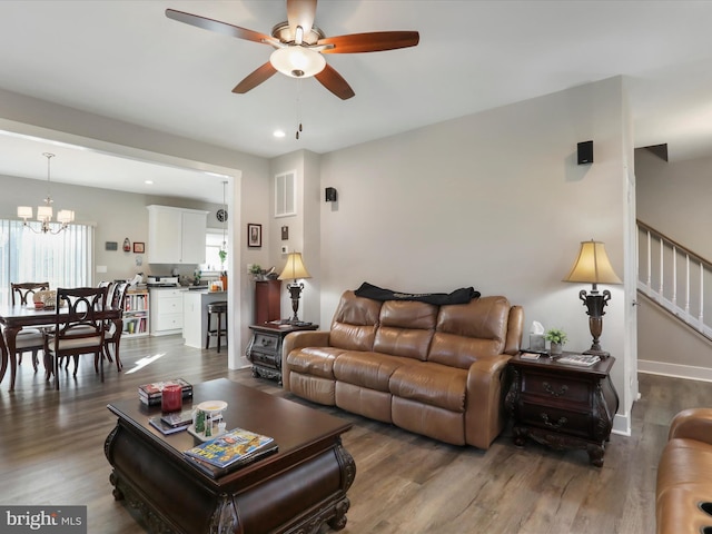 living room with dark wood-type flooring and ceiling fan with notable chandelier