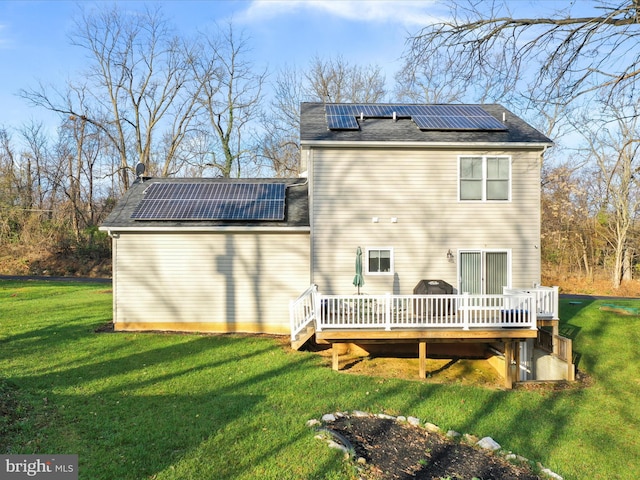 rear view of house with solar panels, a yard, and a wooden deck