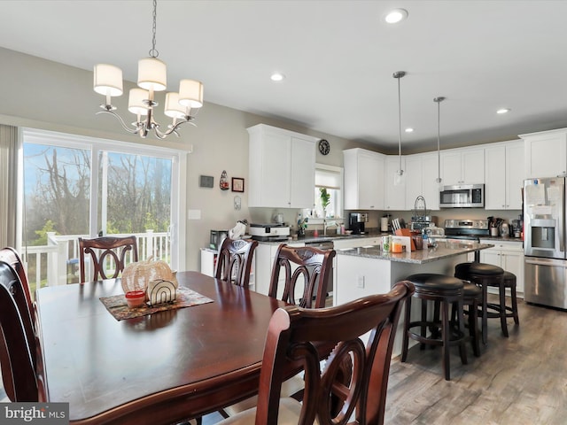 dining space featuring dark wood-type flooring, a notable chandelier, and sink