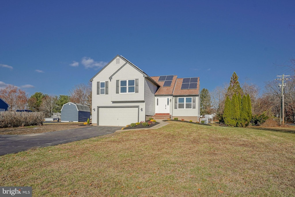 front of property with a front lawn, a garage, and solar panels