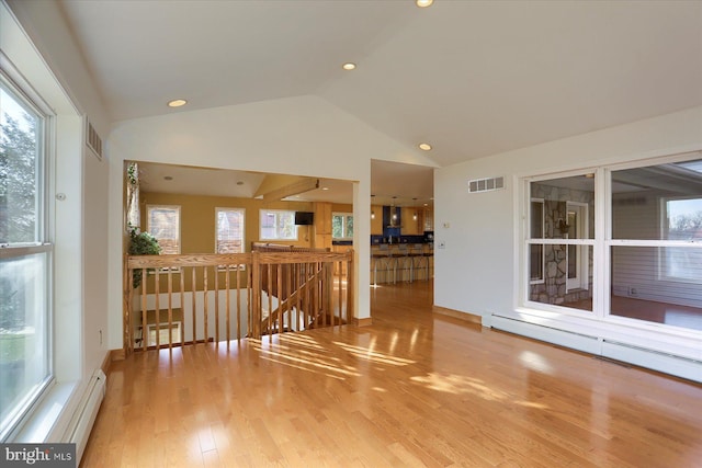 empty room with a baseboard radiator, wood-type flooring, and lofted ceiling