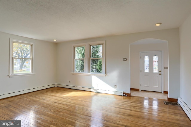 foyer entrance featuring light hardwood / wood-style flooring, plenty of natural light, and a baseboard heating unit