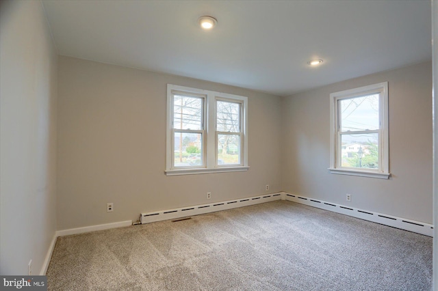 carpeted spare room with a baseboard heating unit