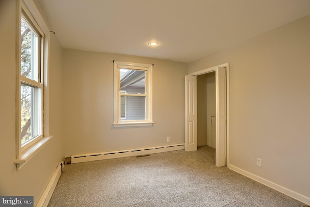 unfurnished room with carpet, plenty of natural light, and baseboard heating