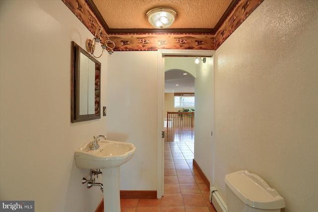 bathroom featuring tile patterned flooring, crown molding, baseboard heating, and a textured ceiling