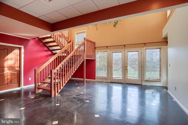 unfurnished living room with a drop ceiling and french doors