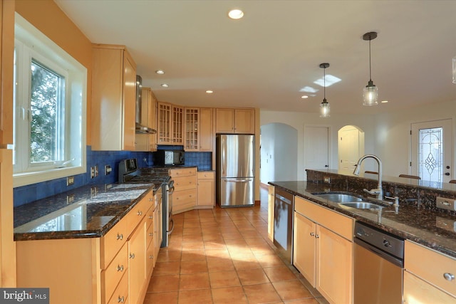 kitchen featuring sink, dark stone countertops, tasteful backsplash, decorative light fixtures, and stainless steel appliances