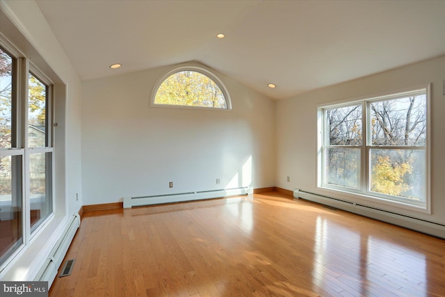 empty room with light wood-type flooring, baseboard heating, and vaulted ceiling