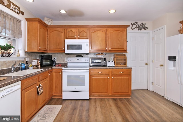 kitchen with tasteful backsplash, white appliances, sink, dark stone countertops, and dark hardwood / wood-style floors