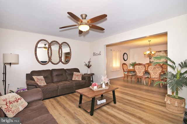 living room featuring ceiling fan with notable chandelier and light hardwood / wood-style flooring