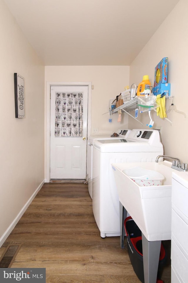 clothes washing area featuring separate washer and dryer and hardwood / wood-style flooring