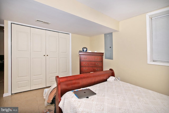 tiled bedroom featuring electric panel and a closet