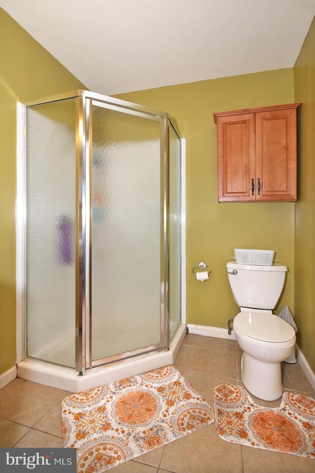 bathroom featuring tile patterned flooring, toilet, and a shower with door