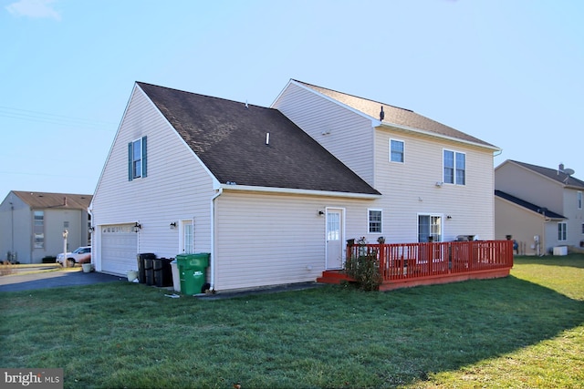 rear view of property featuring a lawn, a wooden deck, and a garage