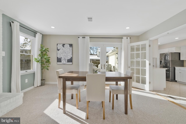 dining space featuring a healthy amount of sunlight, light carpet, and french doors