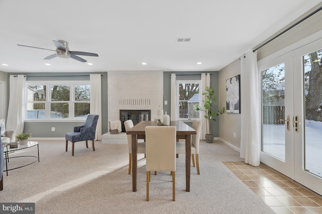 carpeted dining space with a healthy amount of sunlight, a fireplace, and french doors