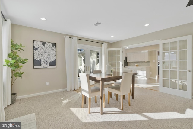 dining space featuring french doors and light colored carpet