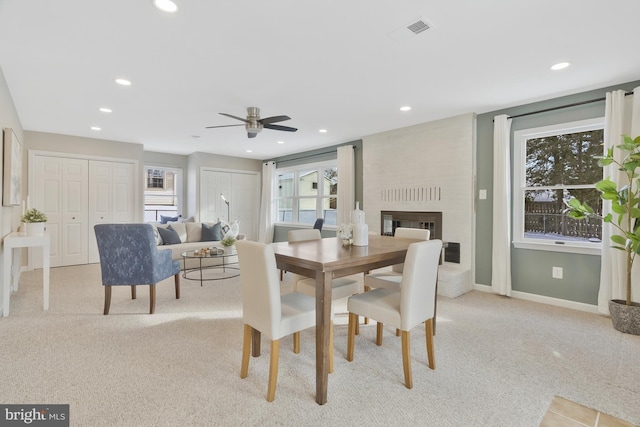 carpeted dining room with a fireplace and ceiling fan