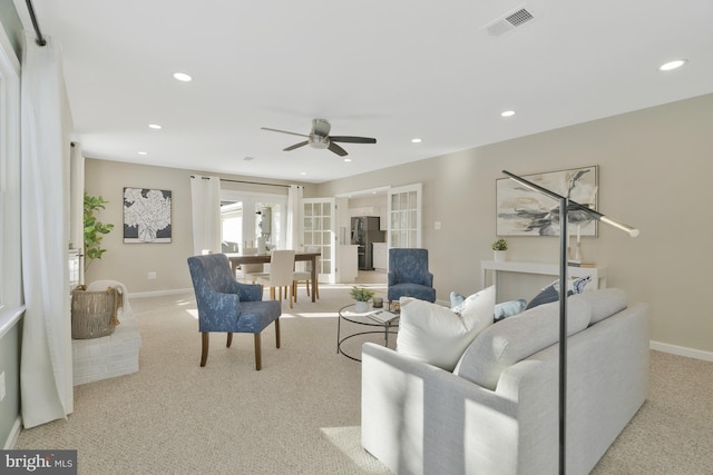 carpeted living room with ceiling fan and french doors