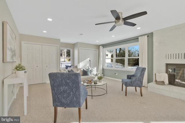 living room with ceiling fan, light colored carpet, and a brick fireplace