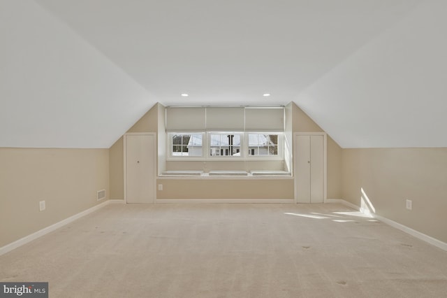 additional living space featuring light colored carpet and vaulted ceiling