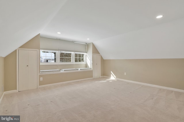 additional living space featuring light carpet and vaulted ceiling