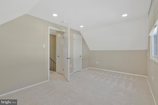 additional living space with light colored carpet and vaulted ceiling