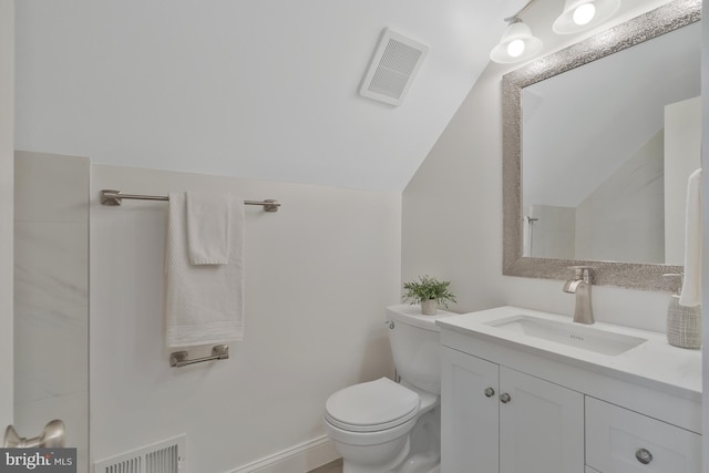 bathroom featuring vanity, toilet, and vaulted ceiling