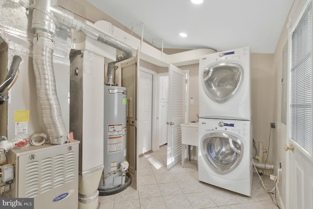 clothes washing area featuring light tile patterned floors, gas water heater, heating unit, and stacked washer / drying machine